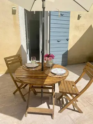 a wooden table with two chairs and an umbrella at Au pied du luberon in Pertuis