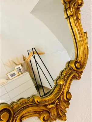 an ornate gold mirror hanging on a wall at La glycine in Saint-Marc-Jaumegarde