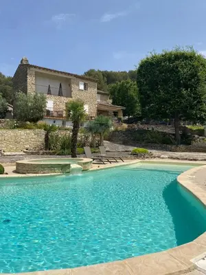 a large blue swimming pool in front of a house at La Souvenance - Listed villa in the hills in Lagnes