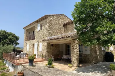 a stone house with a porch and a patio at La Souvenance - Listed villa in the hills in Lagnes