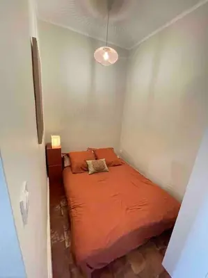 a small bedroom with a bed with an orange comforter at Charmant T2bis coeur historique, Clim, possibilité garage in Aix-en-Provence