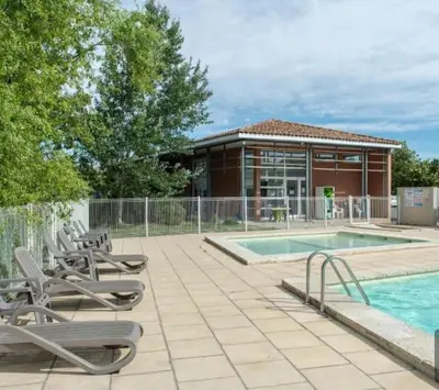 a swimming pool with lounge chairs and a building at Villa Tia - Appartement 2 chambres - piscine - bord de lac in Saint-Saturnin-lès-Avignon