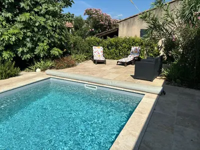 a swimming pool with two chairs and a television in a yard at La Cassiopée in Caromb