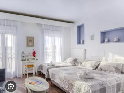a white bedroom with two beds and a table at Luberon family in Apt