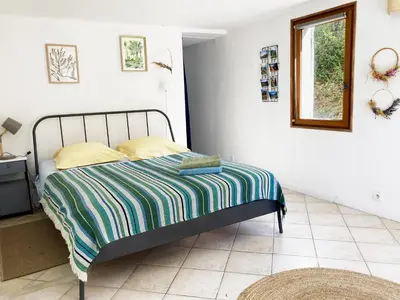 a bedroom with a bed with a striped blanket on it at Les Lavandes in Saignon