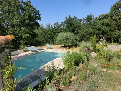 a swimming pool in the middle of a garden at Les Lavandes in Saignon