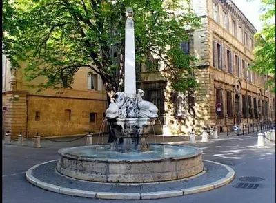 a fountain in front of a building with a monument at Confortable et cosy appartement en centre-ville in Aix-en-Provence