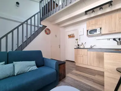 a living room with a blue couch and a kitchen at Joli studio en plein centre historique in Aix-en-Provence