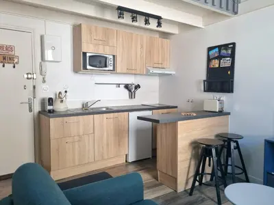 a kitchen with wooden cabinets and a counter with stools at Joli studio en plein centre historique in Aix-en-Provence
