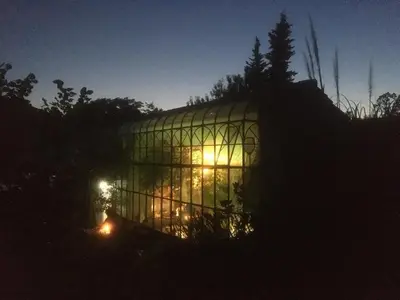 a large glass house with lights in it at night at Ecolodge Au fil de l'eau, avec piscine intérieure et parc arboré in Lagnes