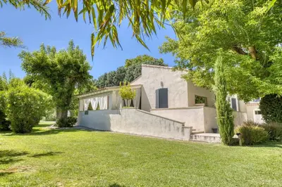 a white house with trees and grass at La Villa aux Cyprès bleu in Le Thor