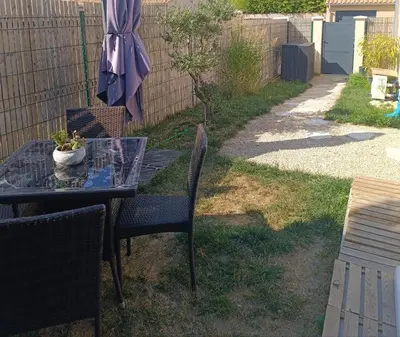 a table and chairs in a yard with an umbrella at La Cigale sous l'Olivier - Chambre , SdB et Salon Privé - Piscine in Les Taillades