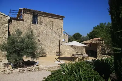 a brick building with an umbrella and a table and bench at Les Pres de Gordes in Gordes