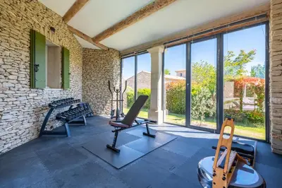 a gym with two exercise machines and windows at La Bastide Des As in Gordes