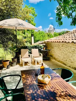 a table with an umbrella and a bottle of wine at Maison Joucas in Joucas