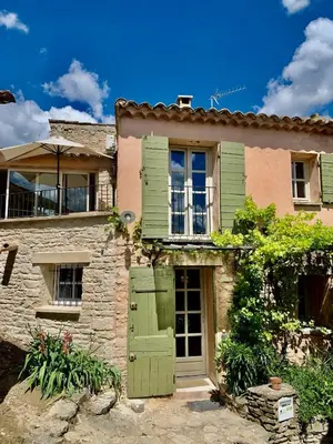 an old stone house with green doors and windows at Maison Joucas in Joucas