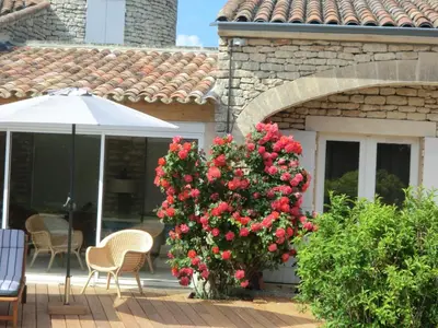 a patio with a bush of red roses and an umbrella at La maison de Inna in Bonnieux