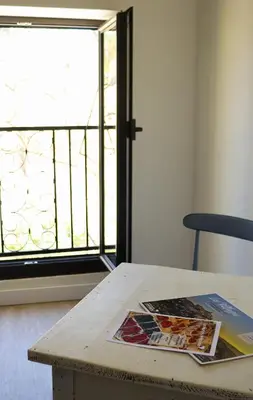 a table with a magazine on it next to a window at Gîte de l'Escanson un temps pour soi in Robion en Luberon