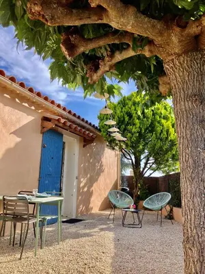 a table and chairs under a tree next to a building at La maison des cerisiers in Bédoin