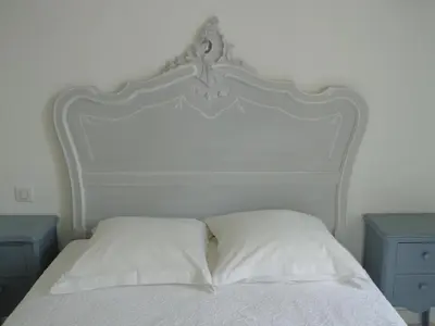 a white bed with white sheets and two blue tables at Domaine Les Rivales in Cavaillon