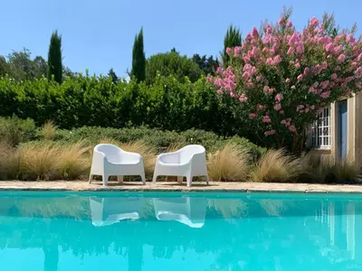 two white chairs sitting next to a swimming pool at LE MAS DE LA TERRE - Chambres d'hôtes in LʼIsle-sur-la-Sorgue