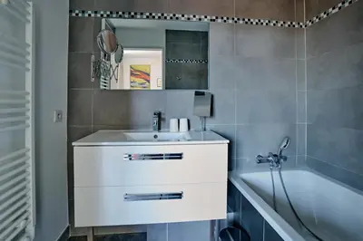 a bathroom with a white sink and a tub at Sérénité au fil de l'eau Appartement de standing in LʼIsle-sur-la-Sorgue