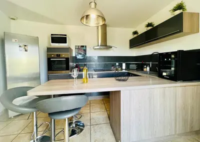 a kitchen with a counter with two bar stools at La villa Louca in Saint-Saturnin-les-Apt