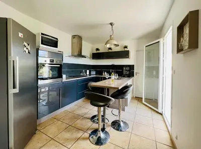 a kitchen with blue cabinets and a table and two stools at La villa Louca in Saint-Saturnin-les-Apt