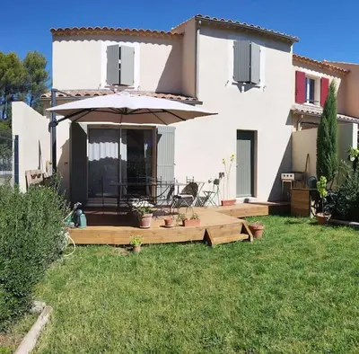 a house with an umbrella in the yard at Charmante maison de vacances en Luberon in Beaumettes