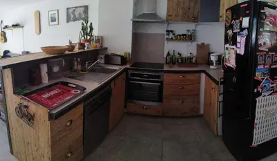 a kitchen with wooden cabinets and a black refrigerator at Charmante maison de vacances en Luberon in Beaumettes