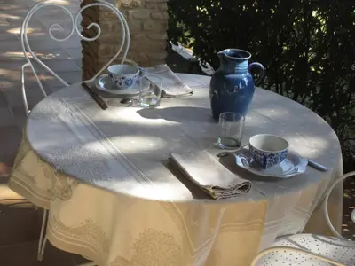 a white table with a blue vase and cups on it at Clos Sainte-Garde in Saint-Didier