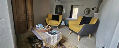 a living room with yellow chairs and a table at maison O jasmin in Lagnes
