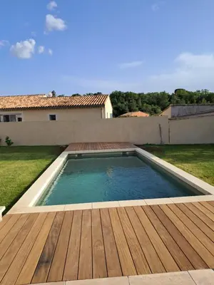 a swimming pool with a wooden deck and a house at Villa SOFIA in Saint-Saturnin-les-Apt