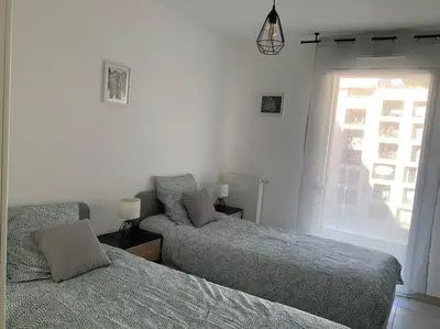 a bedroom with two beds and a window at Logement cosy climatisé avec parking in Aix-en-Provence