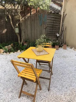 a yellow table and a chair in a backyard at Parenthèse caumontoise . in Caumont-sur-Durance