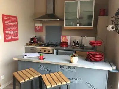 a kitchen with a counter with two wooden stools at Parenthèse caumontoise . in Caumont-sur-Durance