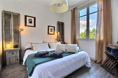 a bedroom with a bed with white sheets and a window at Les copains d'abord ! in Lacoste