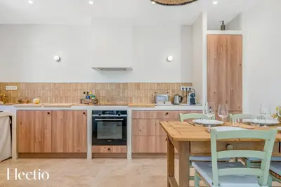 a kitchen with wooden cabinets and a wooden table with chairs at Villa Oliveda - Piscine & Salon Cinéma in Lourmarin