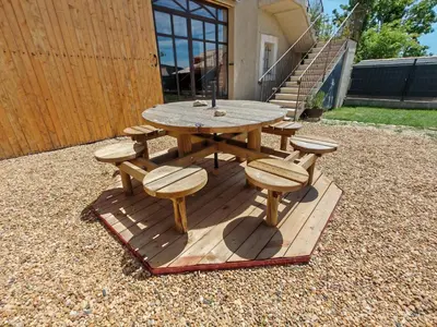 a picnic table and chairs on a wooden deck at La Grange des Joumillons in Saint-Saturnin-les-Apt