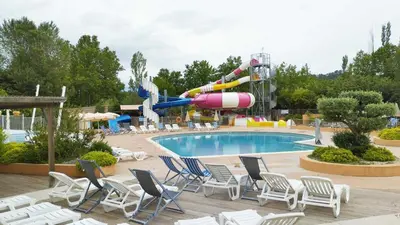a pool with chairs and a water park at Mobil Home vue sur le lac dans un camping 4 étoiles à Cadenet in Cadenet