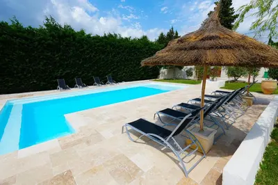 a group of chairs and an umbrella next to a swimming pool at Magnifique villa familiale avec piscine in Caumont-sur-Durance