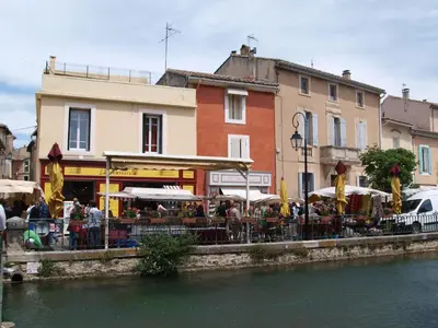 a group of people sitting at a restaurant next to a river at Les Romarins dans le Mas de la PERRINE entre AVIGNON LUBERON Mt VENTOUX in Monteux