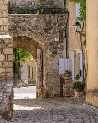 an old stone building with an arch in a street at La loge familiale: 110m2, place rose goudard, AC in LʼIsle-sur-la-Sorgue
