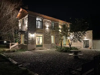 a house with lights on the front of it at night at La palasse in Le Thor