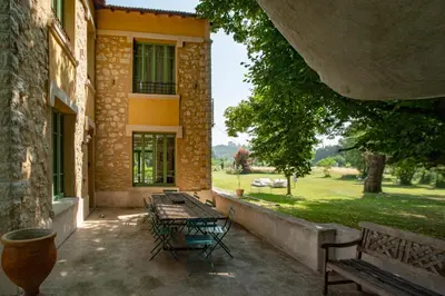 a patio with tables and chairs in front of a building at La palasse in Le Thor