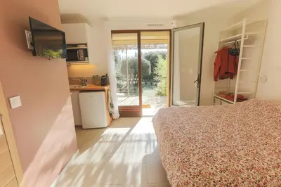 a bedroom with a bed and a kitchen with a sliding glass door at Rouleraventoux, Gîte sportif avec piscine, sauna, salle de sport, jardin in Mormoiron