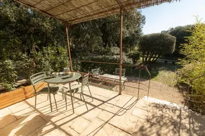a patio with a table and chairs under an umbrella at Rouleraventoux, Gîte sportif avec piscine, sauna, salle de sport, jardin in Mormoiron