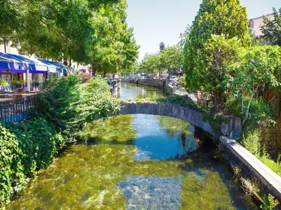 a small river with a bridge in a city at Gîte de L'Olivier, classé, climatisé, jardin avec parking gratuit devant le logement et à 5 minutes du centre-ville à pied in LʼIsle-sur-la-Sorgue