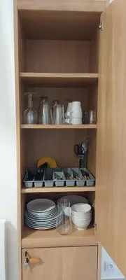 a cupboard with plates and dishes in it at Gîte de L'Olivier, classé, climatisé, jardin avec parking gratuit devant le logement et à 5 minutes du centre-ville à pied in LʼIsle-sur-la-Sorgue