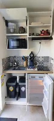 a kitchen with white shelves and a sink and a microwave at Gîte de L'Olivier, classé, climatisé, jardin avec parking gratuit devant le logement et à 5 minutes du centre-ville à pied in LʼIsle-sur-la-Sorgue